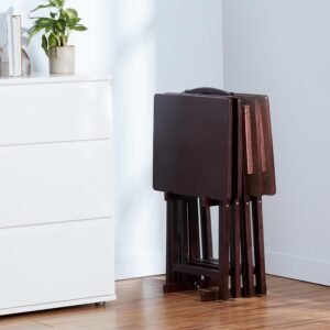 Conjunto de mesas plegables de madera oscura almacenadas en un soporte junto a un mueble blanco.