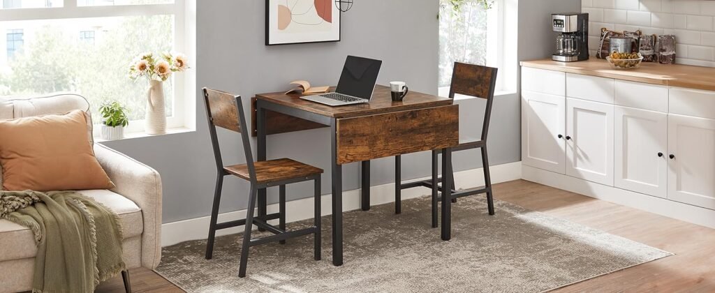 Espacio multifuncional con mesa extensible de madera rústica y estructura metálica negra, acompañada de dos sillas a juego. Decorado con una laptop, taza de café y detalles como flores y plantas en la ventana.