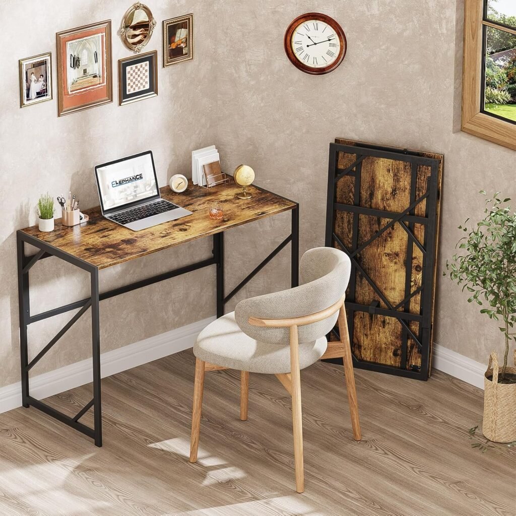Mesa teletrabajo plegable de estilo industrial con tablero de madera y estructura metálica negra en una oficina en casa, acompañado de silla y decoración de pared.