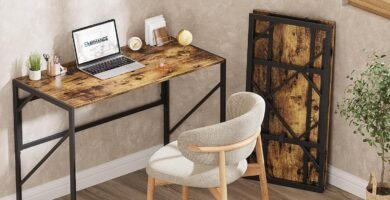 Escritorio plegable de estilo industrial con tablero de madera y estructura metálica negra en una oficina en casa, acompañado de silla y decoración de pared.