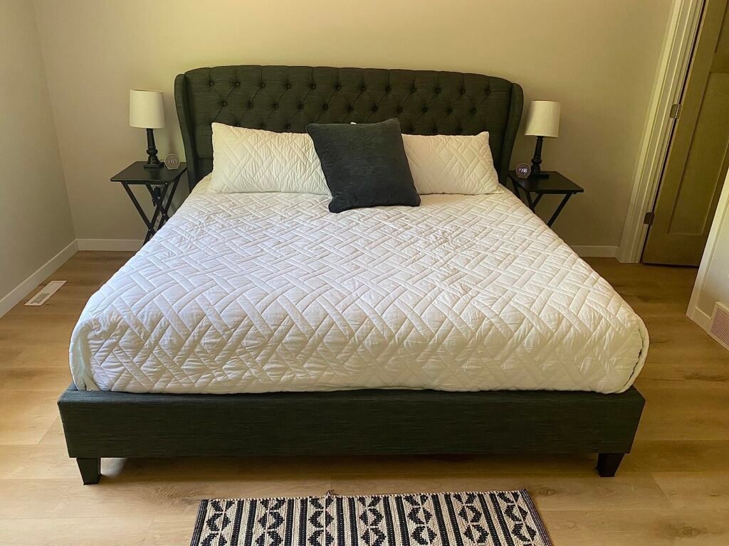 Habitación con una cama grande y dos mesas plegables de madera utilizadas como mesas de noche, cada una con una lámpara encima.