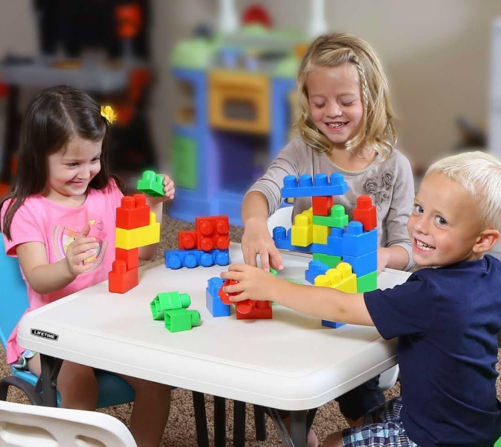 Niños jugando con bloques de construcción coloridos sobre una mesa plegable Lifetime blanca en un ambiente interior diseñado para actividades infantiles.