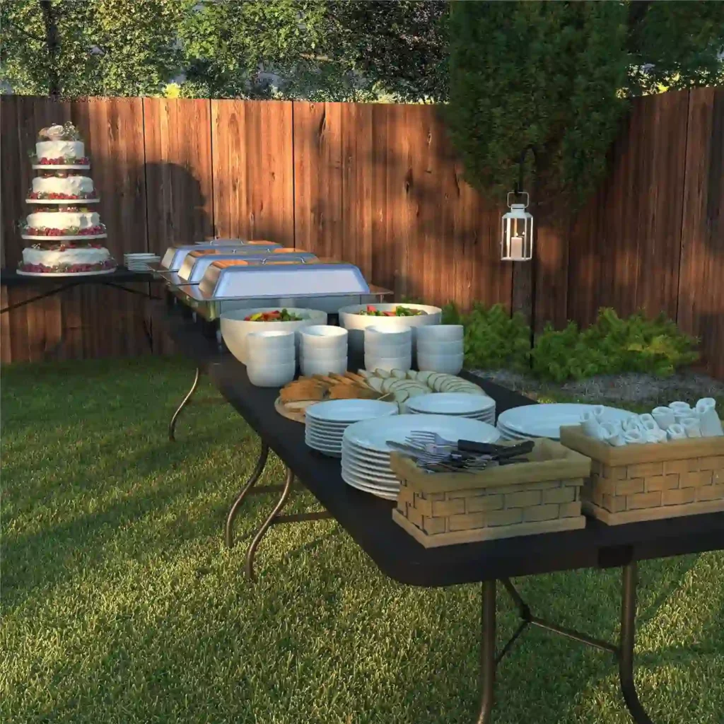 Mejor mesa plegable de catering al aire libre con platos, cubiertos, ensaladas, pan, bandejas térmicas de comida y un pastel de varios niveles en un jardín con césped y cerca de madera.