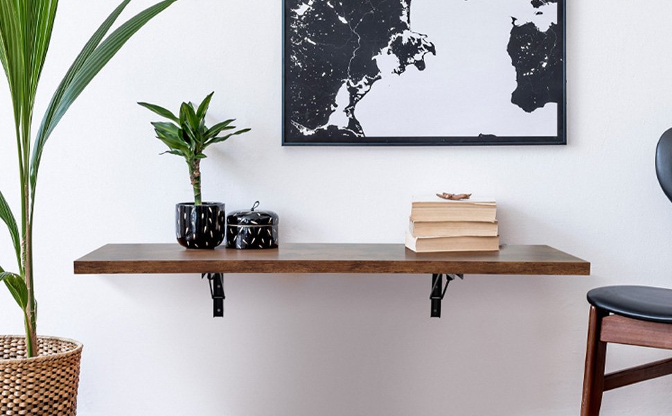 Mesa plegable de pared de madera oscura montado en la pared con soportes metálicos negros, decorado con plantas, libros y elementos decorativos, bajo un mapa enmarcado en blanco y negro.