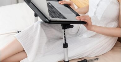 Mujer usando mesa para notebook sobre la cama con patas deslizables.