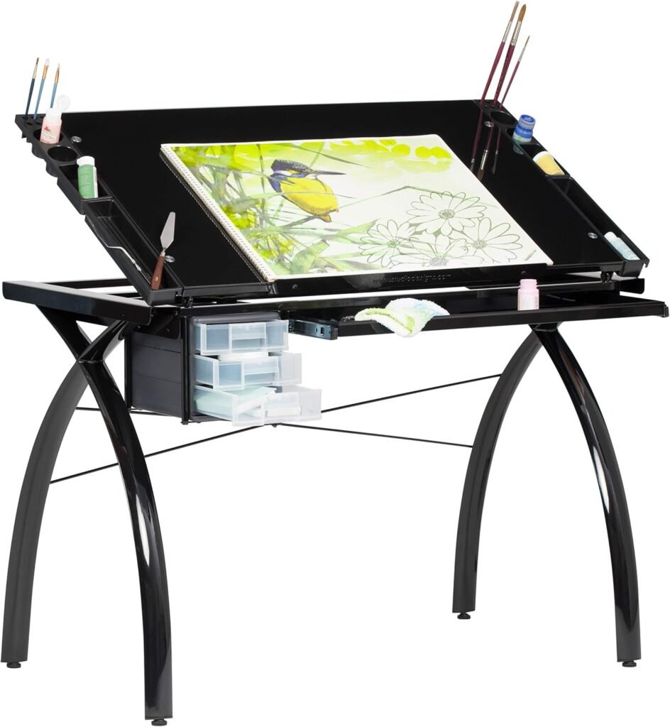 Restirador Plegable SD Studio Designs con superficie de vidrio negro inclinable, equipado con organizadores laterales para pinceles y pinturas, cajones de almacenamiento y una ilustración de ave en proceso.